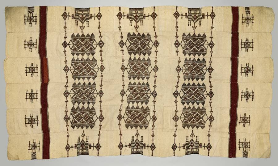 Grande couverture de laine écrue tissée en bandes, ornée de motifs géométriques bruns et noirs et de deux lisérés rouges