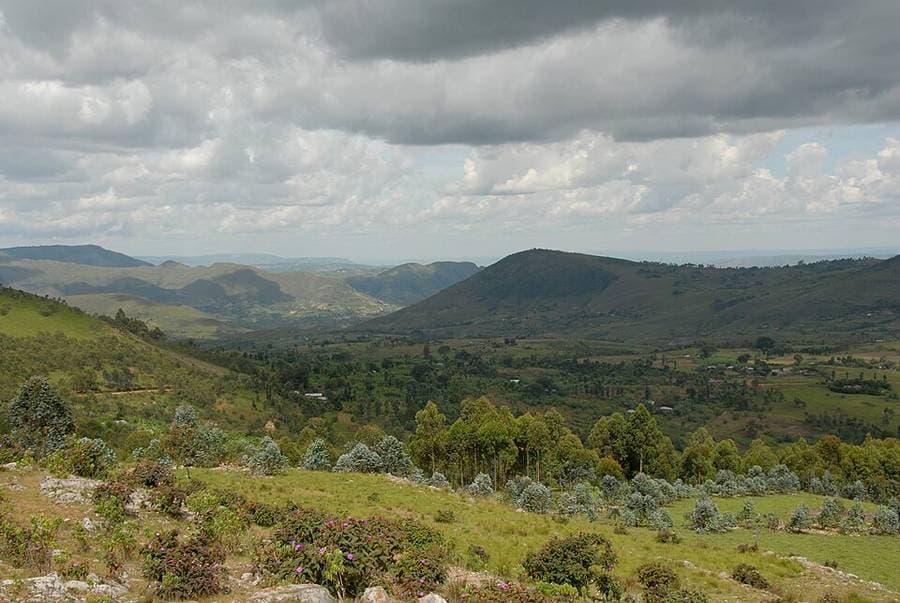 Collines verdoyantes et vallée cultivée sous un ciel nuageux, dans le sud du Burundi