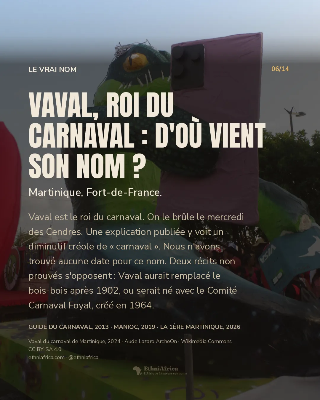 Un énorme personnage-crocodile en papier mâché vert et bleu sombre, assis sur un char, tient un smartphone violet et une carte bancaire « VISA », sous un ciel bleu, avec du public flou en bas à droite.