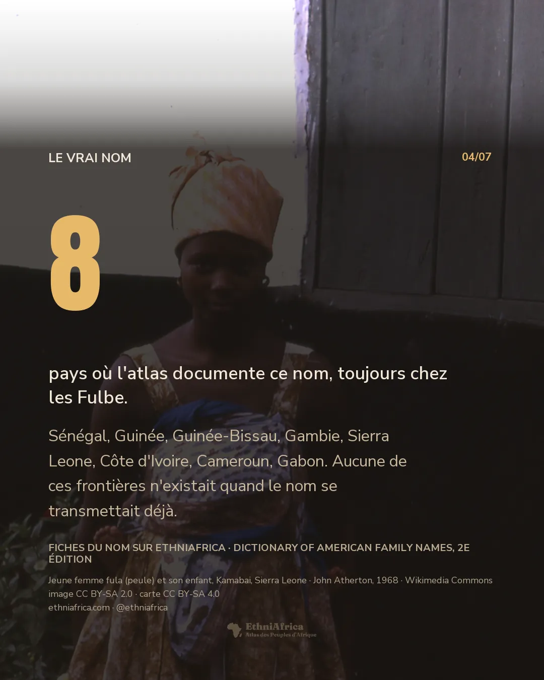 une jeune femme debout de dos, un enfant porté dans un pagne noué à hauteur des reins, devant un mur de terre et un auvent de chaume