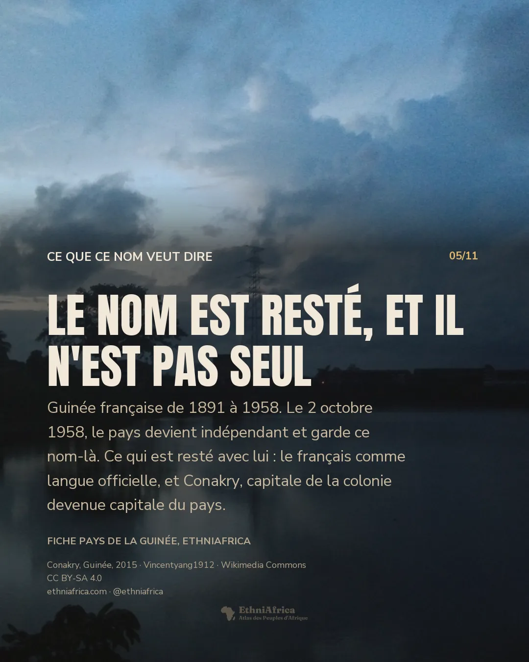Un plan d'eau immobile au crépuscule, reflétant un ciel de gros nuages ; sur la rive opposée, la silhouette d'un grand arbre, un pylône électrique et des bâtiments bas éclairés.